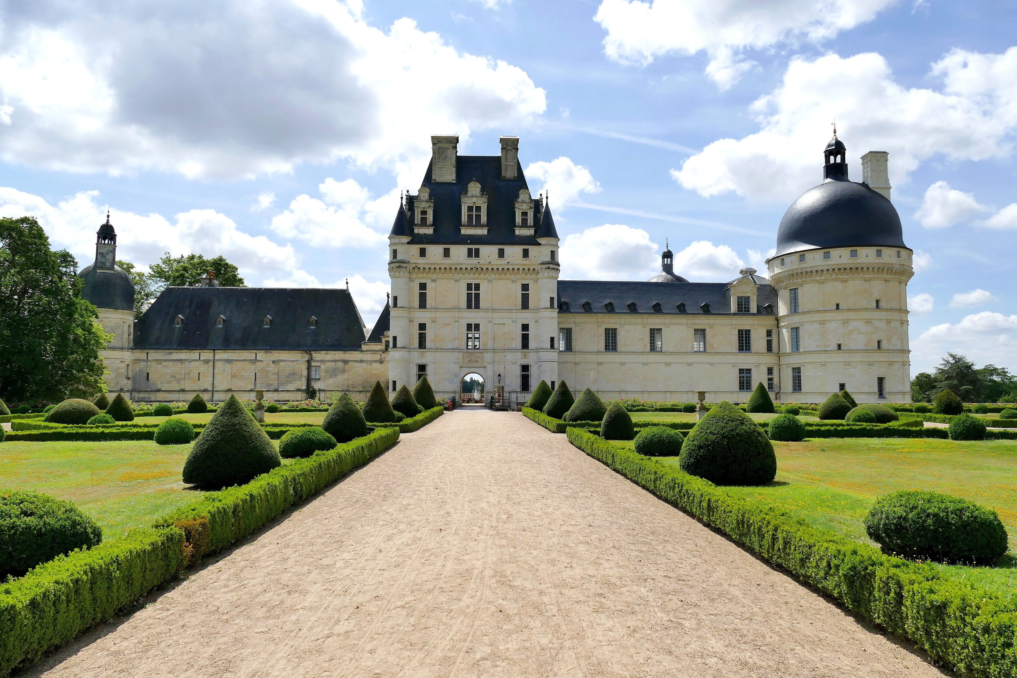 A large historic building with a central dome and symmetrical garden.
