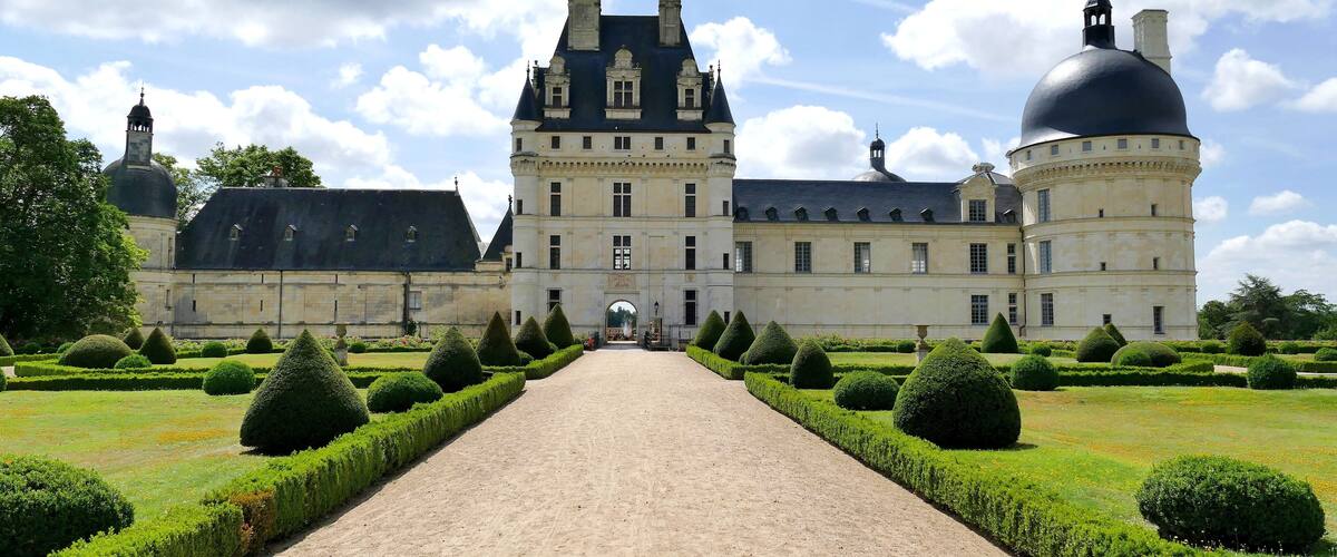 A large historic building with a central dome and symmetrical garden.