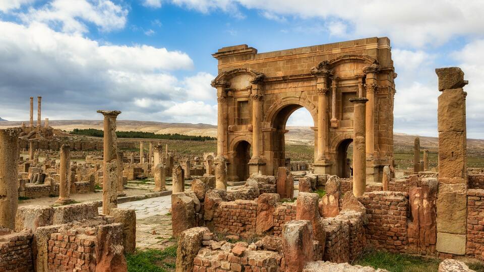 Ancient ruins with a large archway and columns.