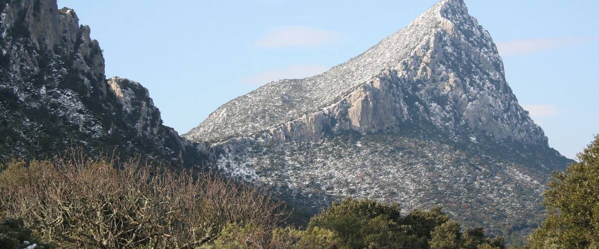 A snow-capped mountain with rugged terrain and sparse vegetation.