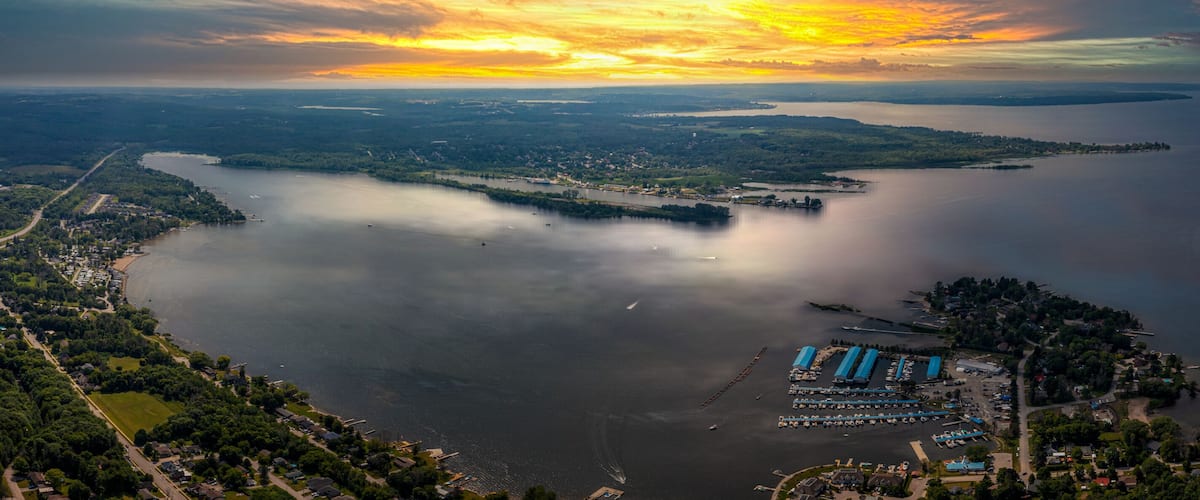 A coastal landscape with a marina, a forested area, and a distant shoreline.