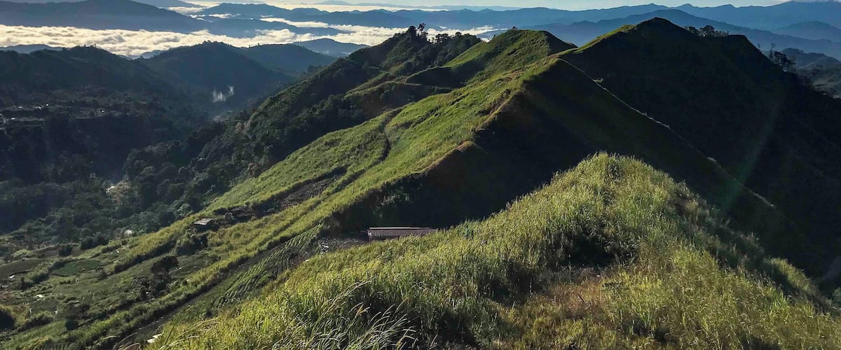 A mountainous landscape with lush green hills and a clear sky.