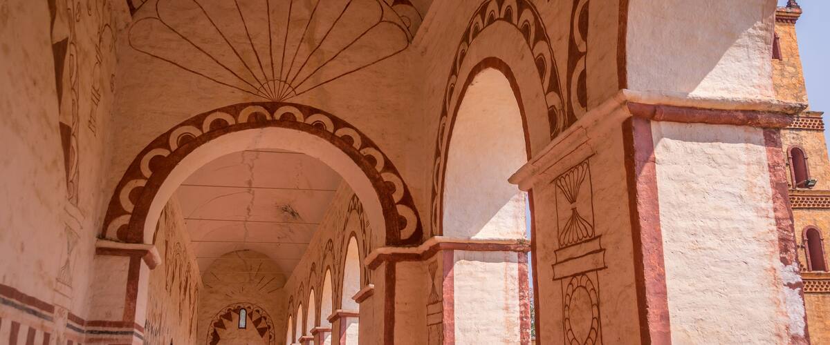 A corridor with arches and detailed wall carvings.