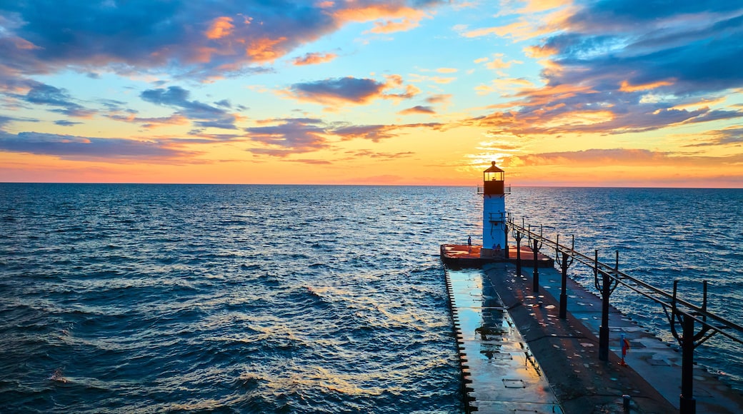 A lighthouse at sunset with the ocean in the foreground.