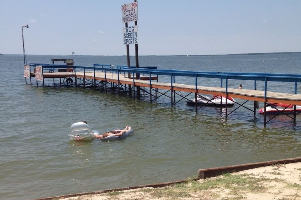 A pier extending into a body of water with a sign advertising pizza and burgers.