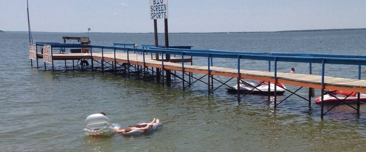 A pier extending into a body of water with a sign advertising pizza and burgers.