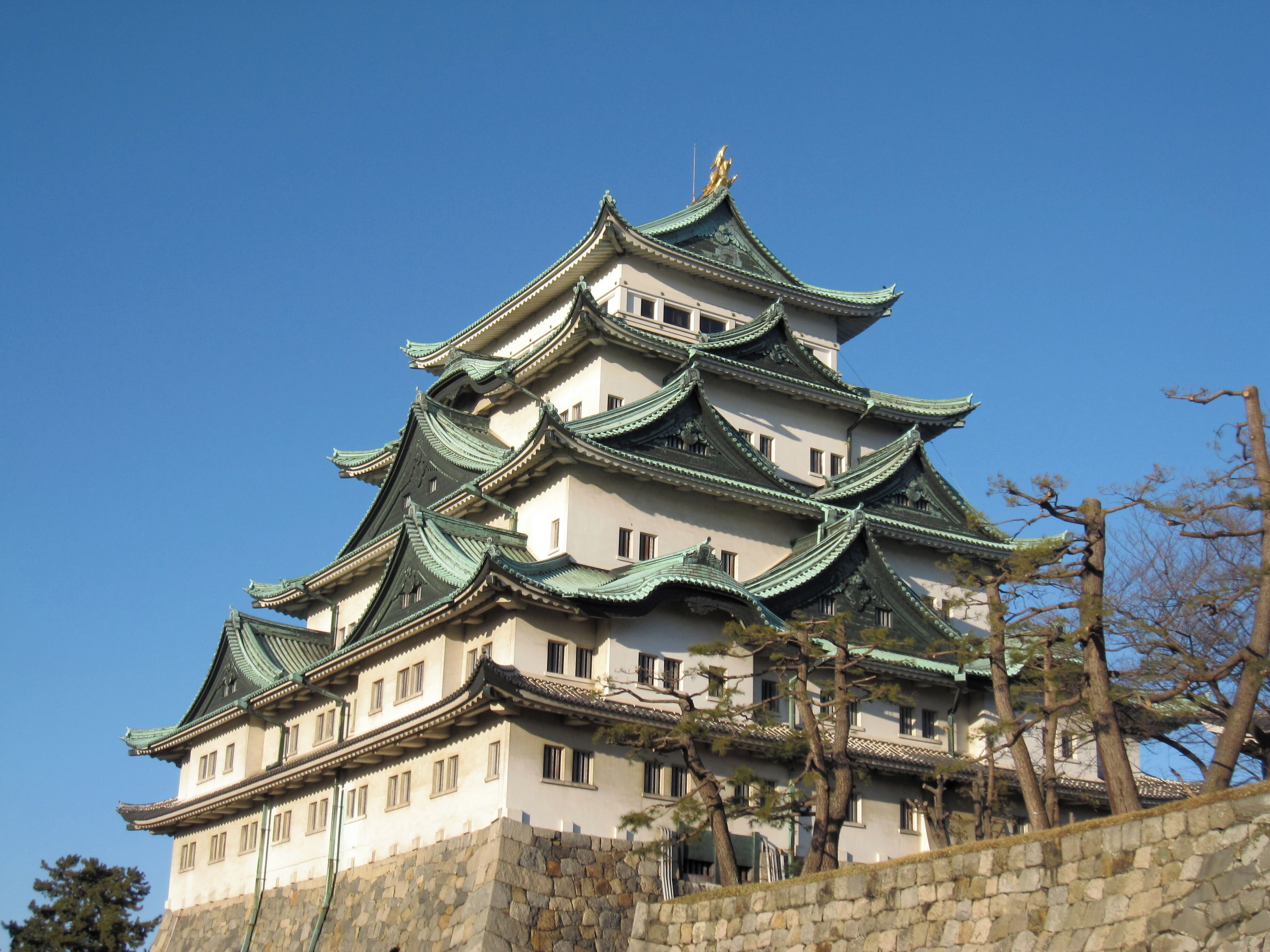 Eine traditionelle japanische Burg mit mehreren Ebenen und grünen Dächern.