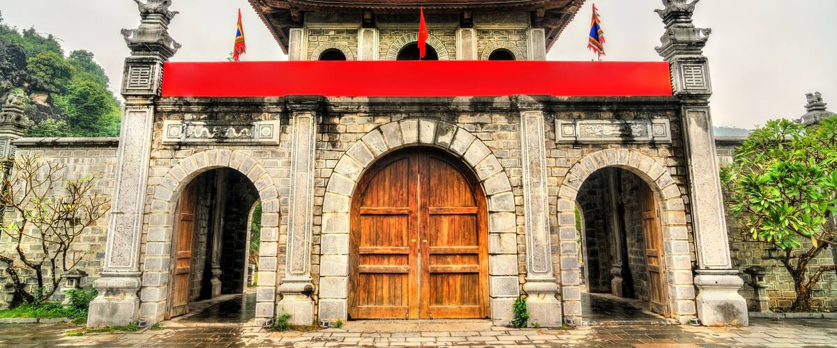 A traditional gate with a red awning, stone pillars, and a tiled roof.