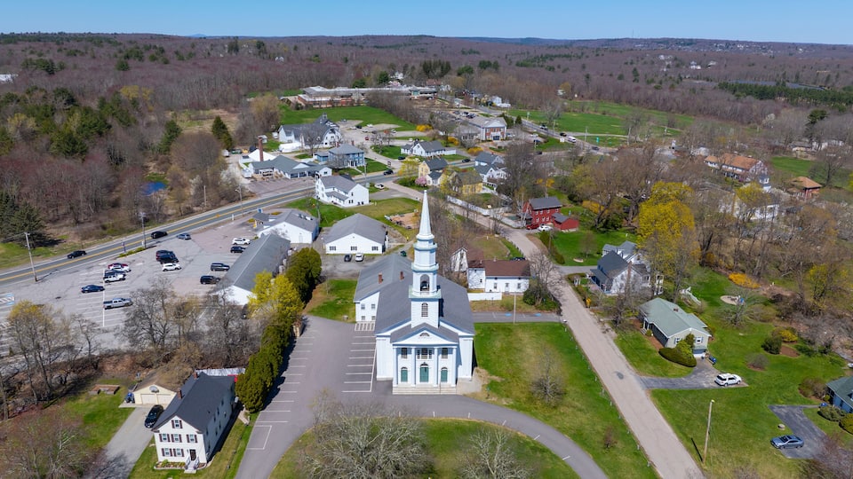 A town with a prominent church, a main road, and surrounding greenery.