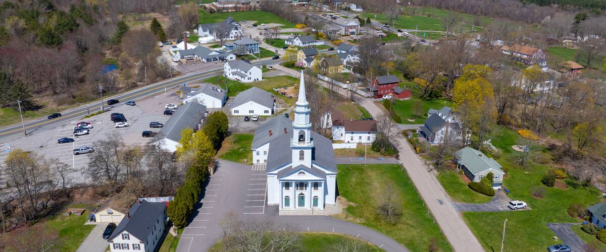 A town with a prominent church, a main road, and surrounding greenery.