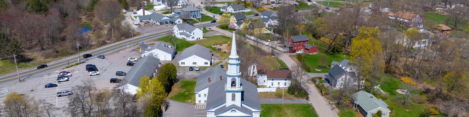 A town with a prominent church, a main road, and surrounding greenery.