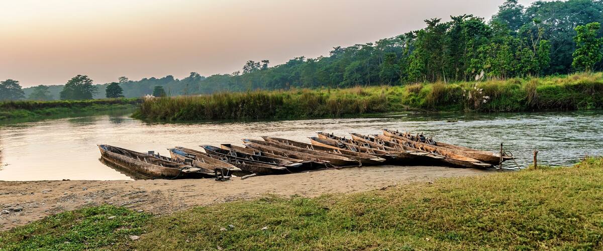 A riverbank with several wooden boats lined up on the shore.