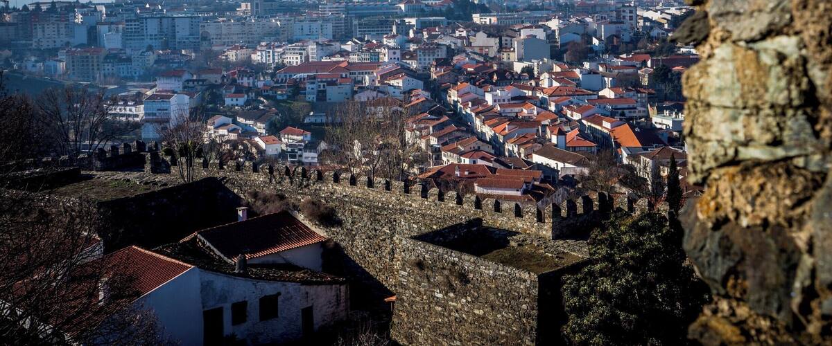 A cityscape with a prominent stone wall in the foreground and a clear blue sky.