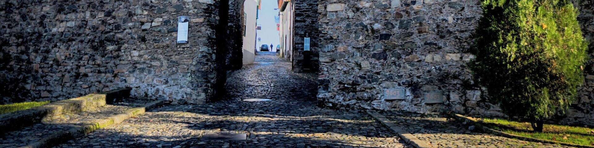A stone archway leading to a castle with battlements.