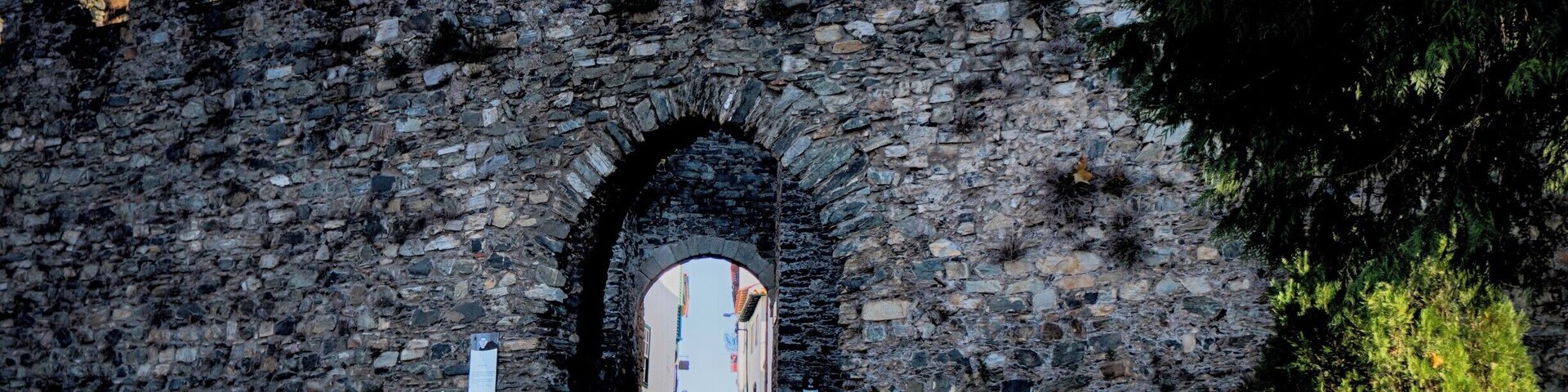 A stone archway leading to a castle with battlements.