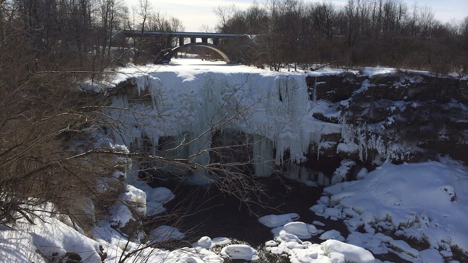 A frozen river with a bridge in the background.