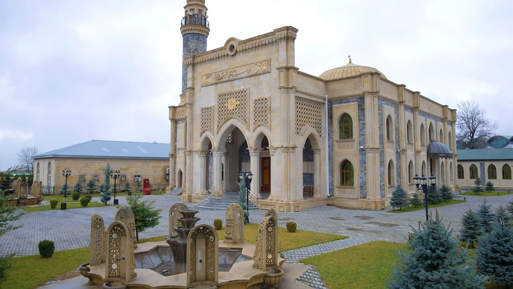 A historic building with intricate architecture, a fountain, and a mosque with a minaret.