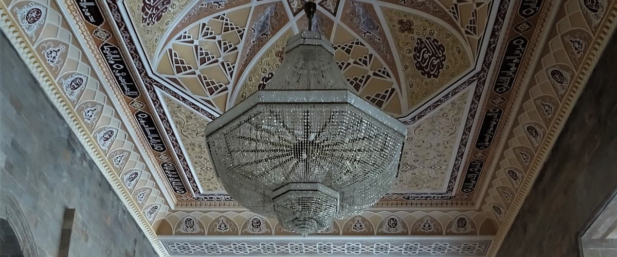 A detailed ceiling with geometric patterns and a central chandelier.