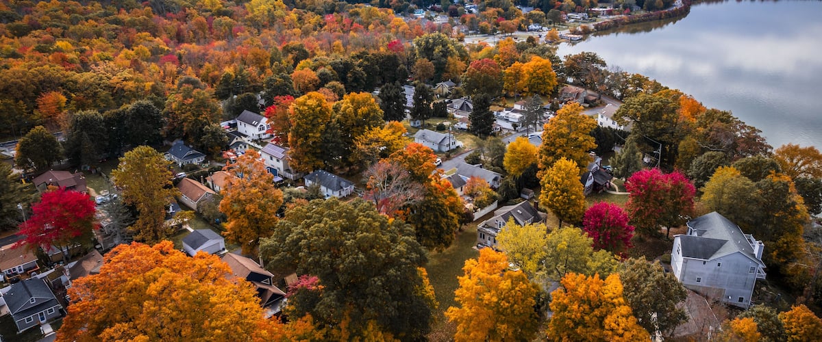 A residential area with autumn-colored trees and a lake.