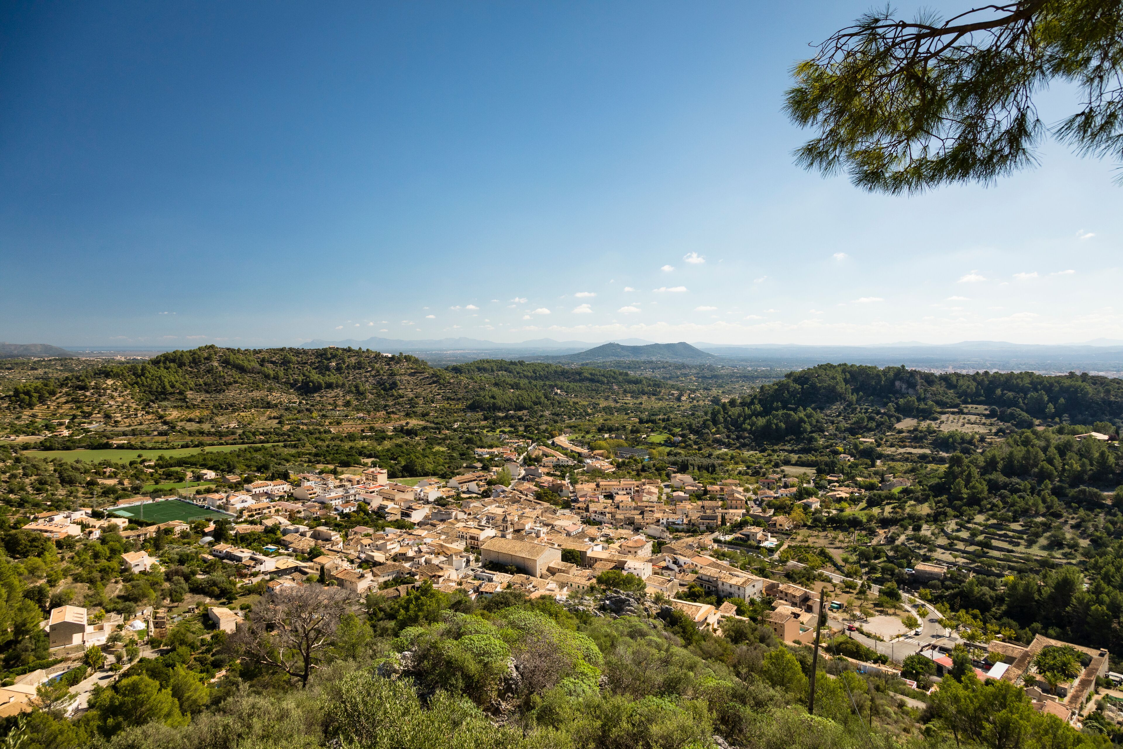A panoramic view of a town nestled in a valley with rolling hills in the background.