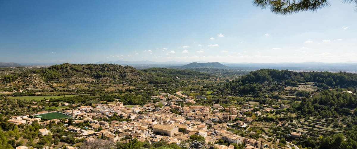 A panoramic view of a town nestled in a valley with rolling hills in the background.