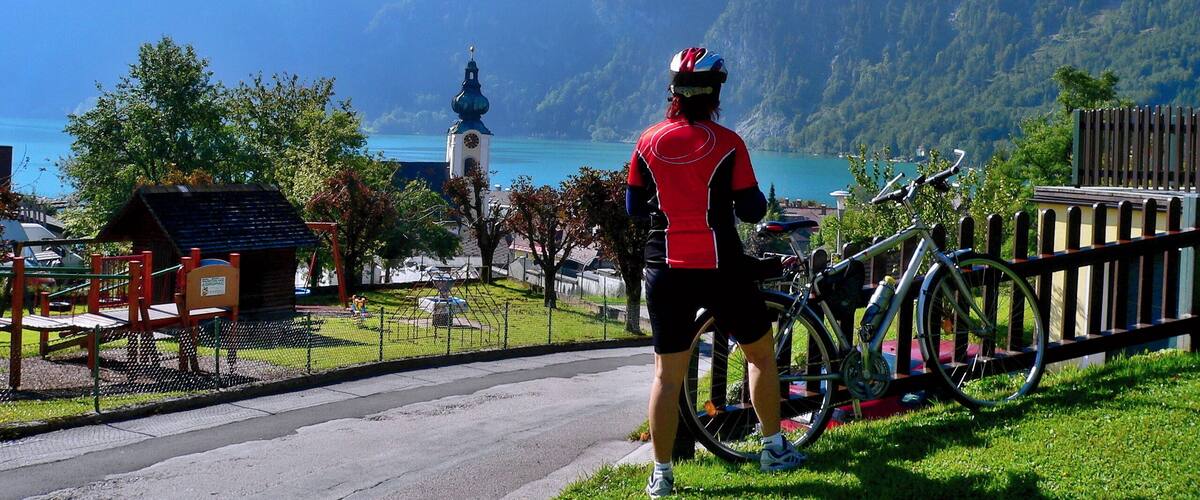A cyclist overlooking a lake with mountains in the background.