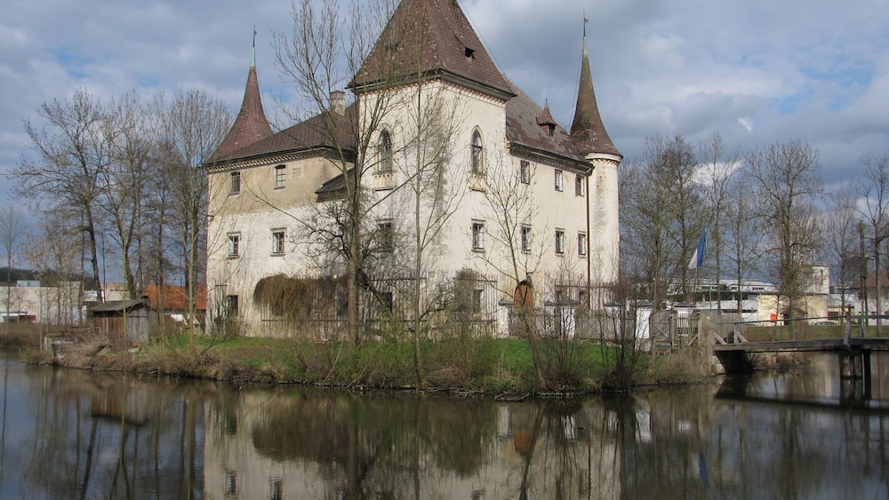 A historic building with multiple towers by a calm river.