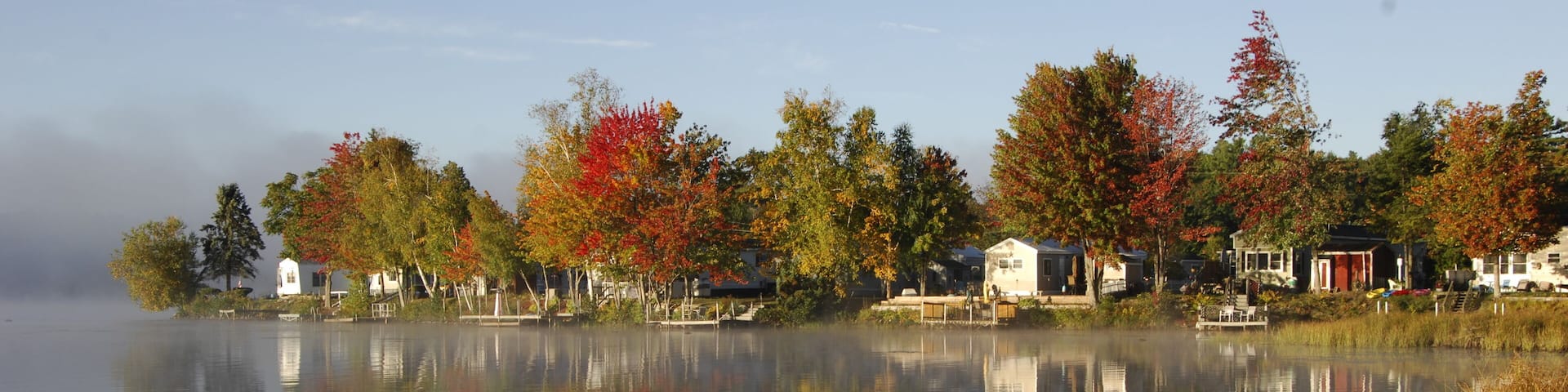A calm lake with reflections of trees and buildings.