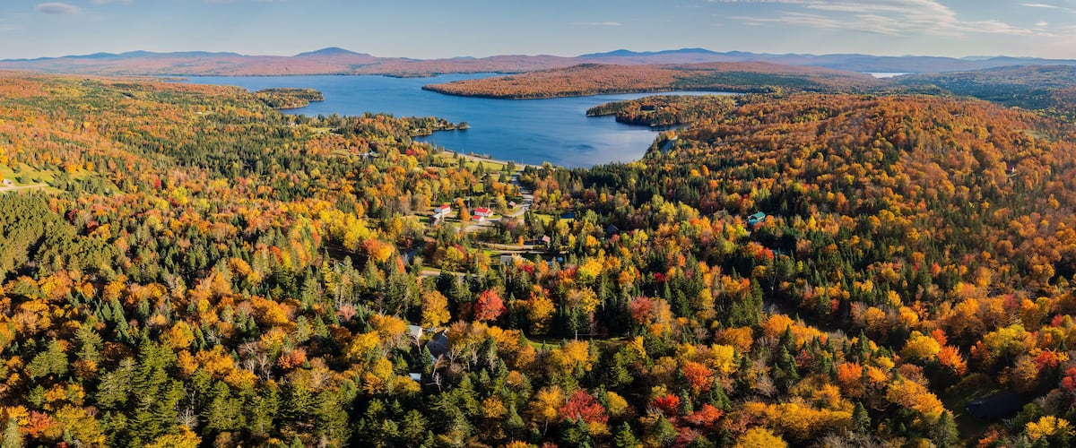 A lake surrounded by autumn-colored trees and distant mountains.