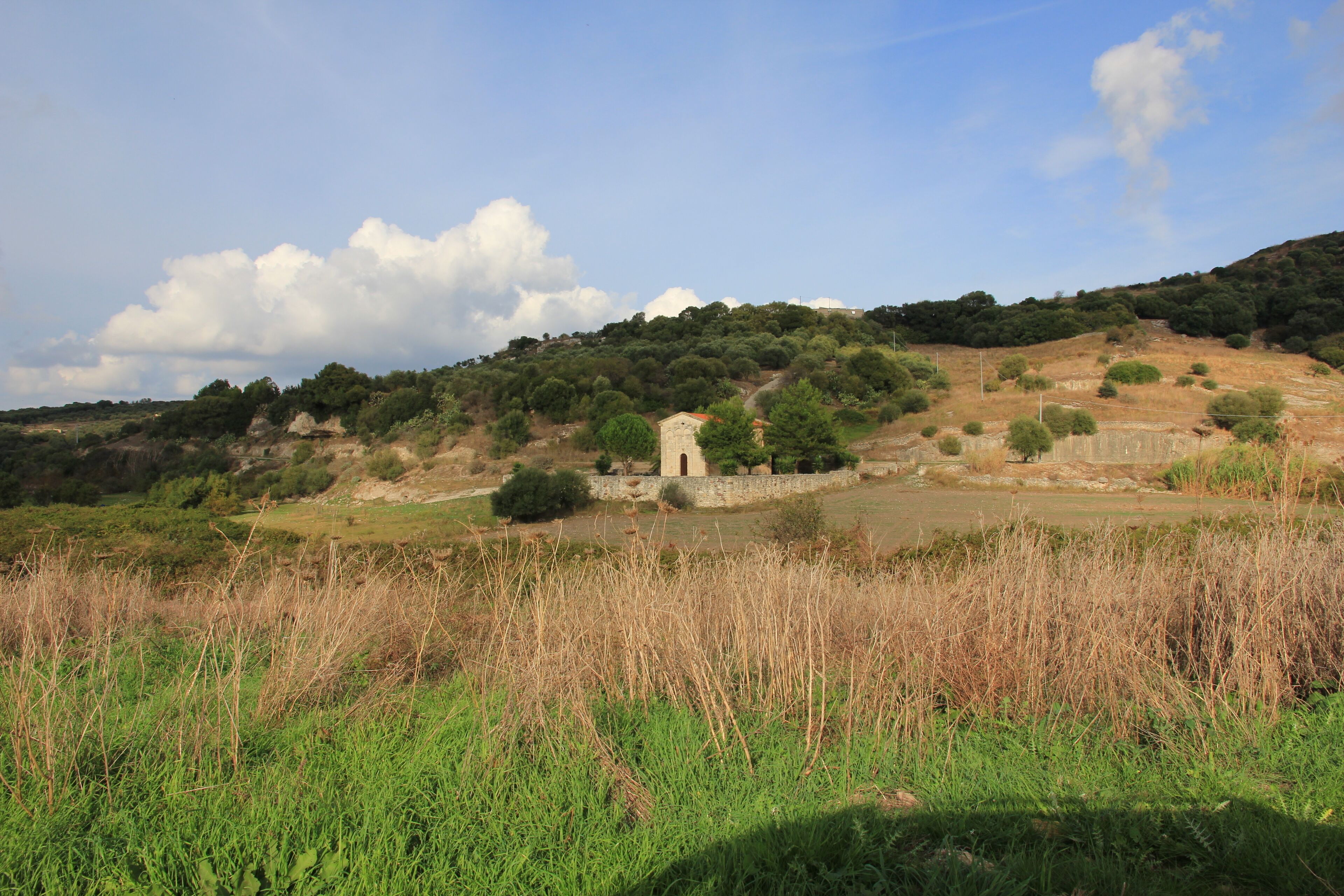 A rural landscape with a stone tower, rolling hills, and a clear sky.