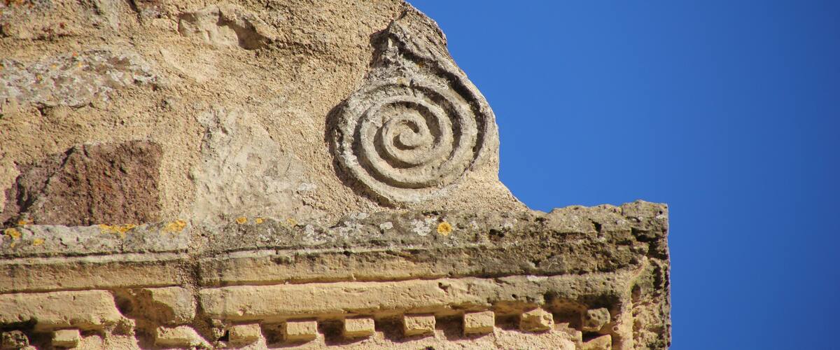A stone wall with a spiral carving and a rectangular recess.