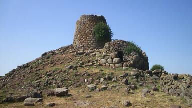 A stone tower on a hill with sparse vegetation.
