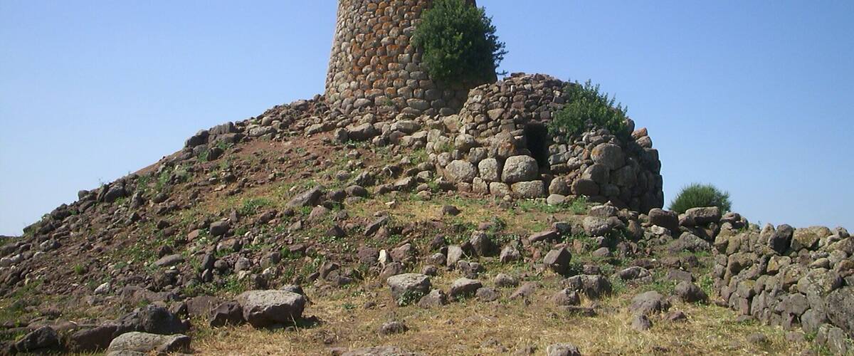 A stone tower on a hill with sparse vegetation.