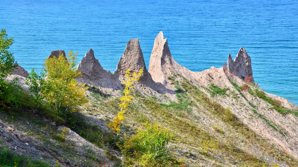 A coastal landscape with rocky formations and a clear blue sea.