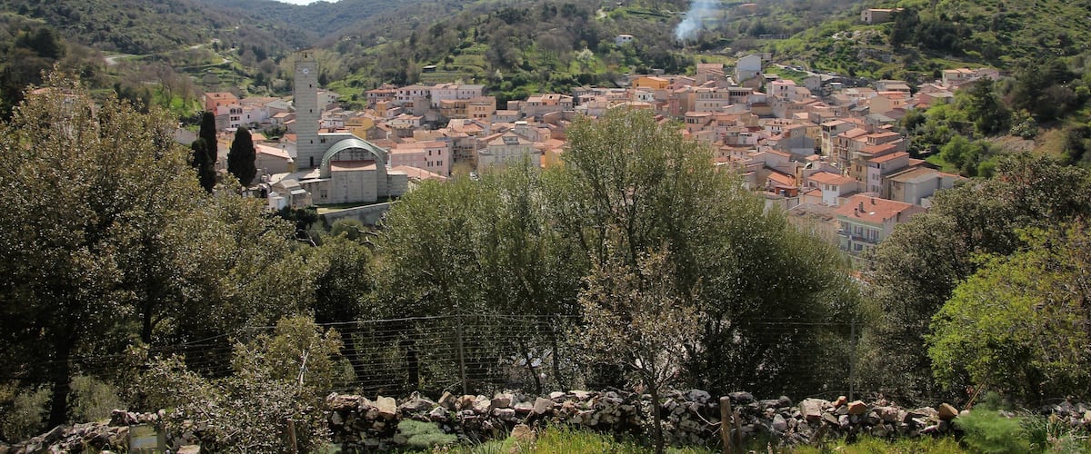 A town nestled in a valley with a prominent church and a hilltop structure emitting smoke.