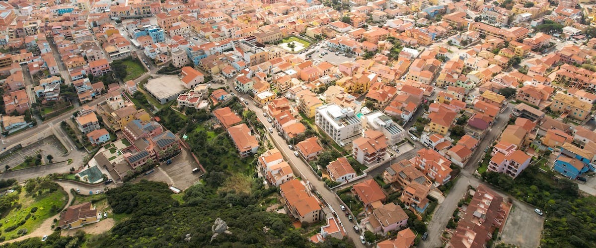 An aerial view of a coastal town with densely packed buildings, a marina, and a coastline.