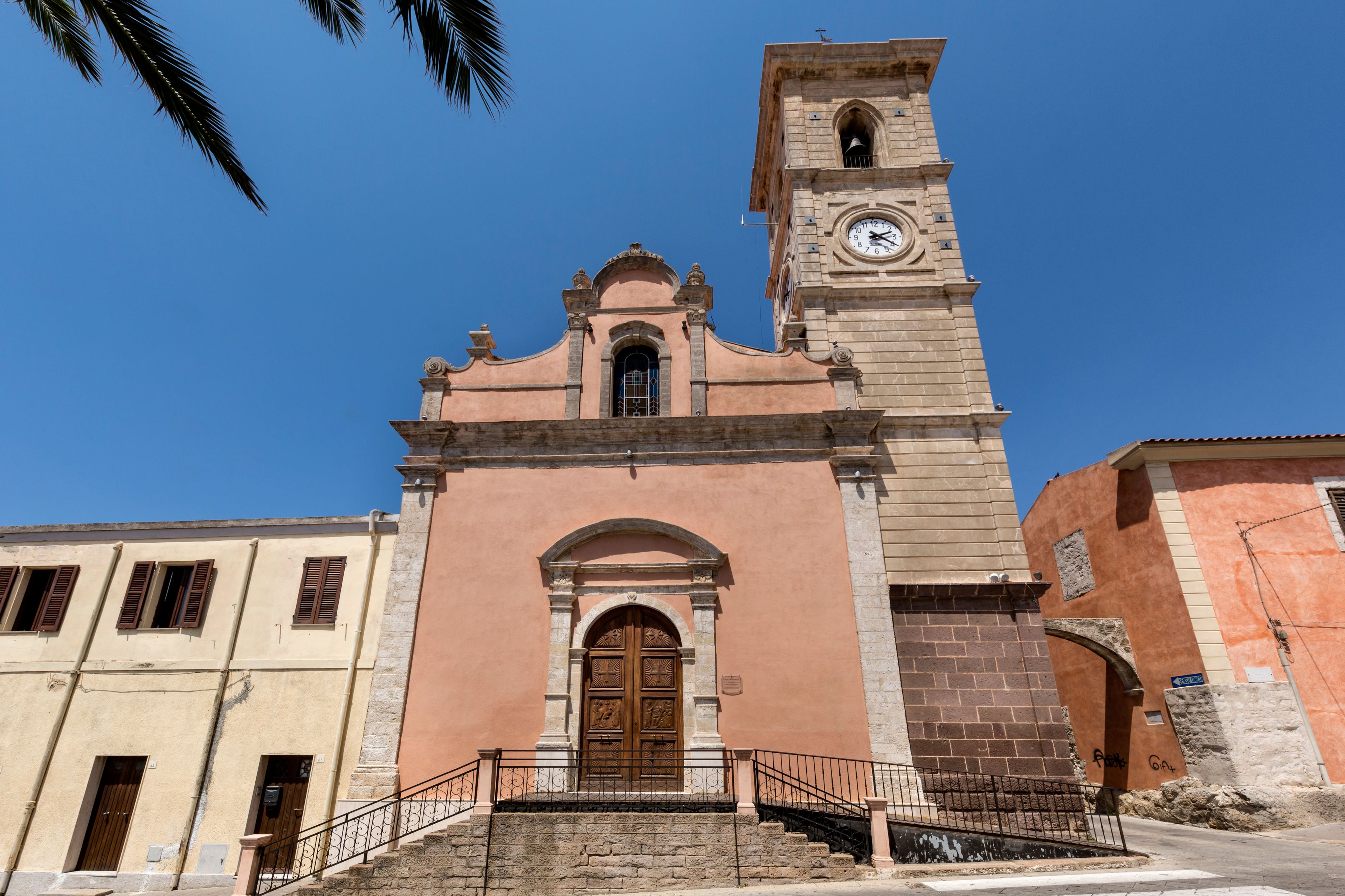 A church with a clock tower, a wooden door, and a staircase leading up to the entrance.