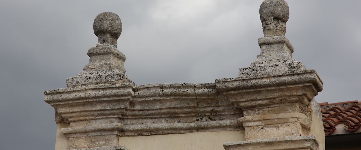 A stone balustrade with spherical finials against a cloudy sky.