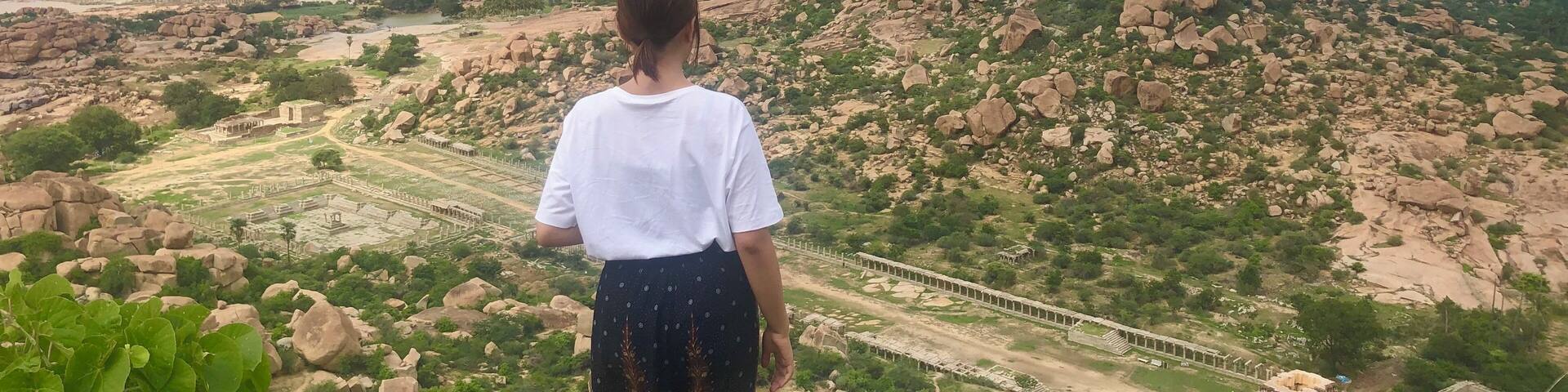 Una persona contemplando un paisaje con terreno rocoso y ruinas antiguas.