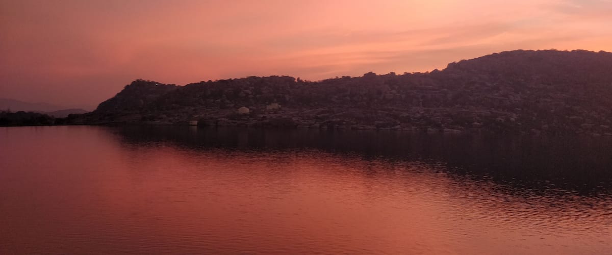 A sunset over a lake with a mountain in the background.