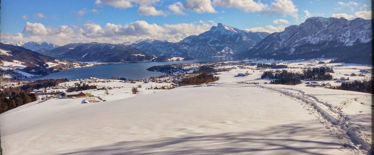 A snowy landscape with a lake, mountains, and a clear sky.