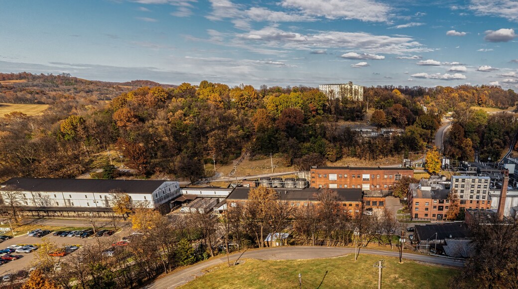 Aerial View of a historic bourbon whiskey distillery and an ageing warehouse on a hill in the background. Autumn colorful fall foliage panorama in Lynchburg Tennessee U.S.A.