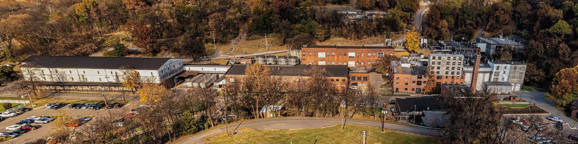 Aerial View of a historic bourbon whiskey distillery and an ageing warehouse on a hill in the background. Autumn colorful fall foliage panorama in Lynchburg Tennessee U.S.A.