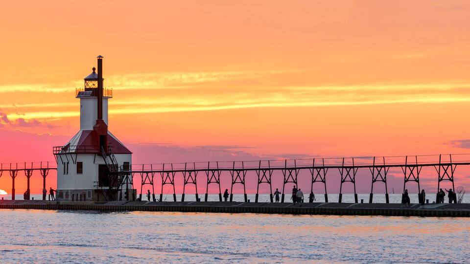 A lighthouse and pier at sunset.