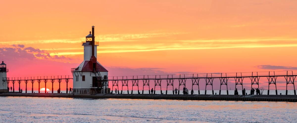 A lighthouse and pier at sunset.