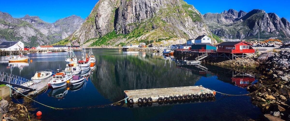 A harbor with boats, a wooden dock, and a mountain in the background.
