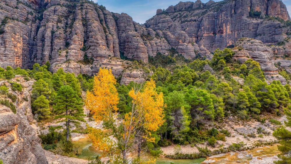 A mountainous landscape with rocky cliffs and a river.