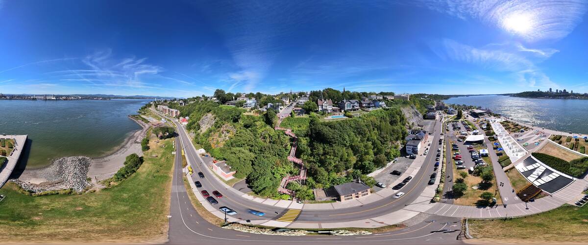 A panoramic view of a coastal town with a curved road, waterfront, and residential buildings.