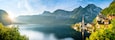 Un lac paisible, entouré de montagnes, une église dotée d’un clocher et des maisons traditionnelles qui bordent le rivage.