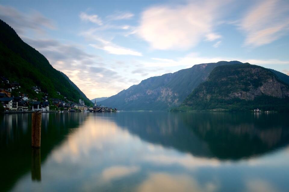 A calm lake with a mountain on the right and a village on the left.